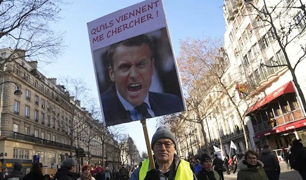 A protester holds a portrait of French President Emmanuel Macron during a protest against Macron. (AP)