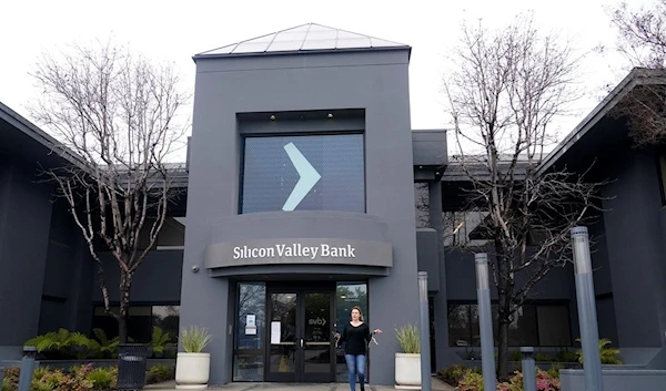 A property managment representative gestures while asking reporters to clear the entrance area to Silicon Valley Bank in Santa Clara, Calif., Friday, March 10, 2023 (AP Photo/Jeff Chiu)