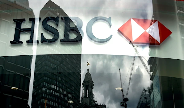 The HSBC logo is seen through a window where buildings are reflected on to, at a branch in London (AP).