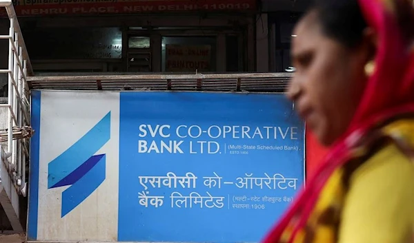 A woman walks past the bank The Shamrao Vithal Co-op. Bank Ltd. (SVC) at a market in New Delhi, India, March 13, 2023. (Reuters)