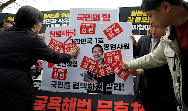 Protesters attach stickers on an image of South Korean President Yoon Suk Yeol during a rally against the South Korean government's announcement of a plan over the issue of compensation for forced labors in Goyang, South Korea, Wednesday, March 8, 2023.