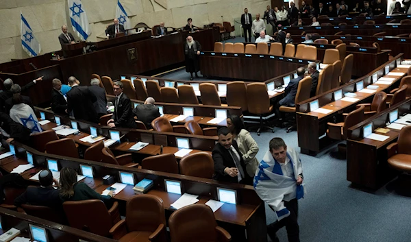 An Israeli lawmaker is pursued by security as he drapes himself in the national flag in protest, in the Knesset, against a contentious plan to overhaul the country's legal system, in Al-Quds, Monday, Feb. 20, 2023 (AP).