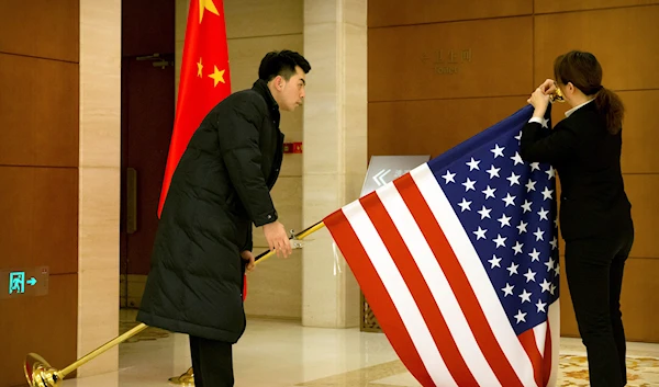 Chinese staffers adjust a US flag before the opening session of trade negotiations between US and Chinese trade representatives at the Diaoyutai State Guesthouse in Beijing, China, February 14, 2019 (AP).