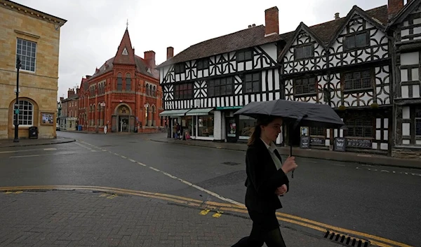 A woman walks alone a street in Stratford-upon-Avon, Warwickshire, England, Tuesday, Feb. 28, 2023 (AP Photo/Kin Cheung)