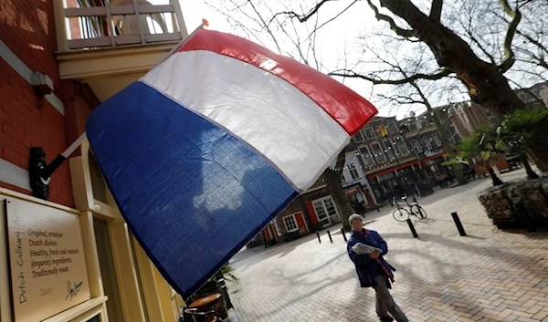 A woman walks past a national flag, the day before a general election, in Delft, Netherlands, March 14, 2017. (Reuters)