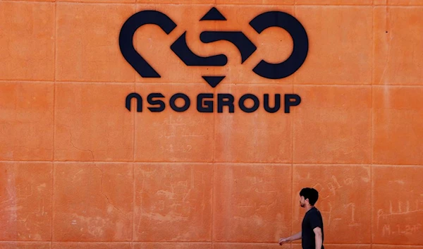 A man walks past a logo of the NSO Group. (Reuters)