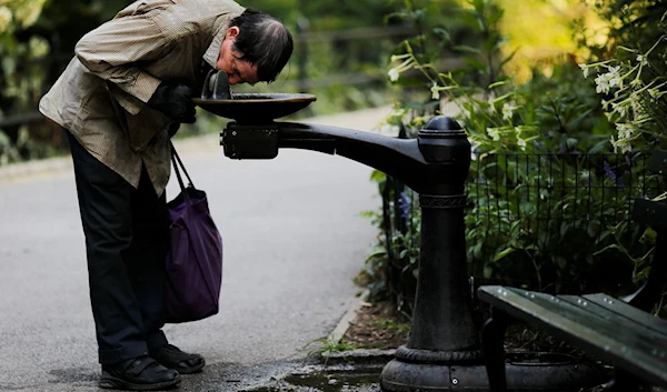 A man drinks from a water fountain on a hot summer day in Central Park, Manhattan, New York, US, July 1, 2018 (Reuters).