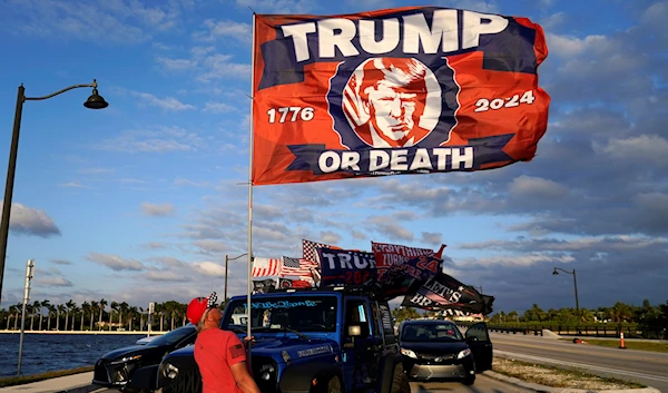 A supporter of former President Donald Trump raises a flag outside of Trump's Mar-a-Lago estate, Monday, March 20, 2023, in Palm Beach, Florida (AP).