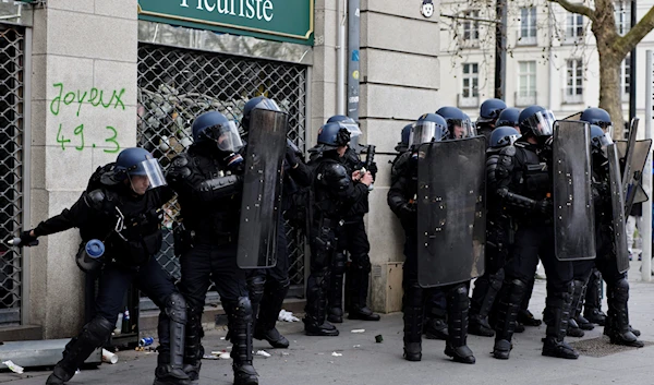 A police officer throws a grenade during a demonstration in Nantes, western France, Saturday, March 18, 2023. (AP)