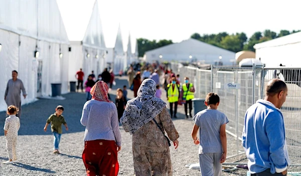 Afghan refugees walk through an Afghan refugee camp at Joint Base McGuire Dix Lakehurst, N.J., on Sept. 27, 2021 (AP Photo/Andrew Harnik, File)