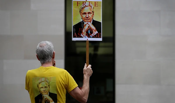 A demonstrator holds a banner outside Westminster Magistrates Court in London, Friday, Aug. 14, 2020. (AP)