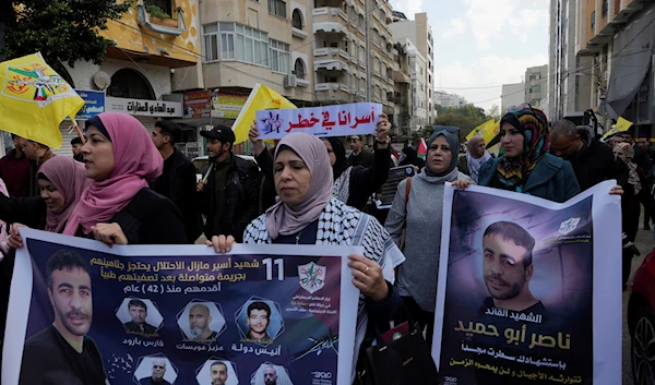 Palestinians march with posters of Nasser Abu Hamid, a veteran Palestinian prisoner who died in Israeli custody last week, in Gaza City, Tuesday, Dec. 27, 2022 (AP Photo/Adel Hana)