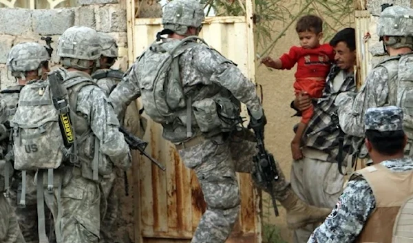 A US occupation soldier kicks a home in Baghdad, traumatizing a dad and his son on November 4, 2008. (Reuters)