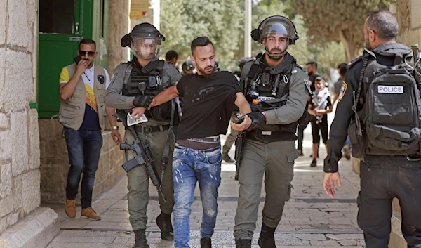 Israeli security forces detain a man at the entrance of Jerusalem's al-Aqsa Mosque compound, 21 May 2021 (AFP)