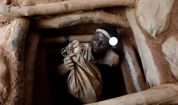 An artisanal miner climbs out of a gold mine with a bag of rocks broken off from inside the mining pit at the unlicensed mining site of Nsuaem Top in Ghana, November 24, 2018. (REUTERS)