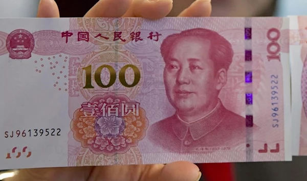 A staff member displays a 100-yuan RMB banknote at the Bank of China Tower in Hong Kong. (AP)