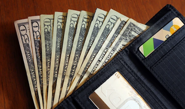 Cash is fanned out from a wallet in North Andover, Mass., June 15, 2018 (AP).