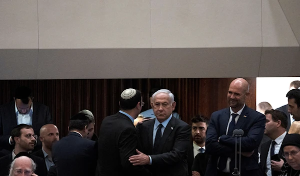 Israeli Prime Minister Benjamin Netanyahu, embraces lawmaker Simcha Rotman on the floor of the Knesset, in occupied Al-Quds, occupied Palestine, March 27, 2023 (AP)