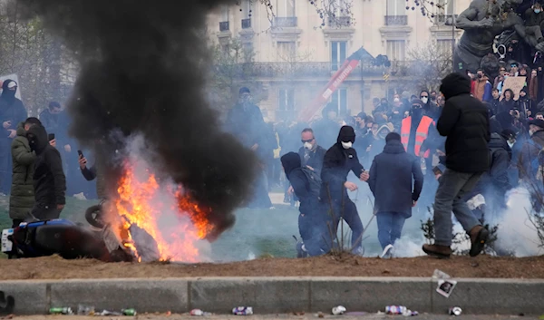 Youths gather near a burning scooter after a demonstration, March 28, 2023, in Paris (AP)