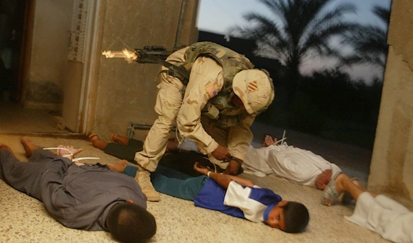 In this June 21, 2003 file photo, U.S. Army Spc. Dandrea Harris handcuffs a family with plastic ties during night raid in Habaniyah, Iraq (AP Photo/John Moore)