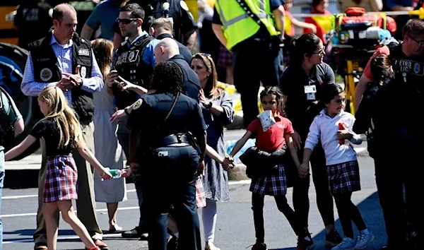 Students from the Covenant School hold hands Monday after getting off a bus to meet their parents at a reunification site after a mass shooting at the school in Nashville. (Reuters)