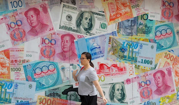 A woman walks by a money exchange shop decorated with different countries currency banknotes at Central, a business district in Hong Kong, Aug. 6, 2019 (AP Photo/Kin Cheung)