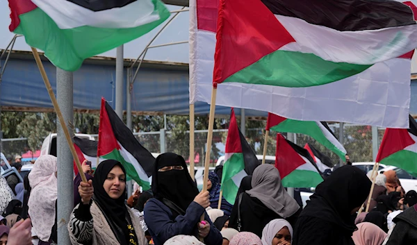 Palestinian women wave flags during a rally marking the 47th anniversary of Land Day, east of Gaza City, occupied Palestine, March 30, 2023 (AP)