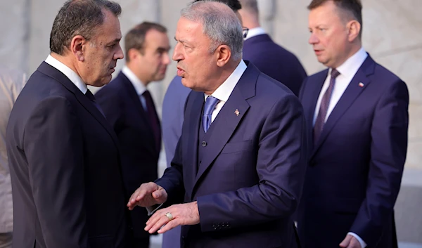 Turkish Defense Minister Hulusi Akar, center, speaks with Greek Defense Minister Nikolaos Panagiotopoulos during a group photo of NATO defense ministers at NATO headquarters in Brussels, Thursday, June 16, 2022 (AP).