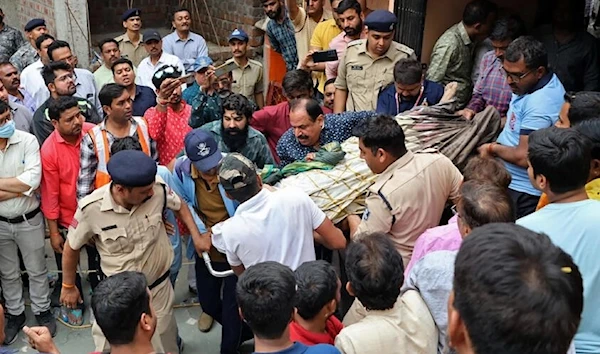 Police officers hold a body for one of the dead worshippers after the incident. (AFP)