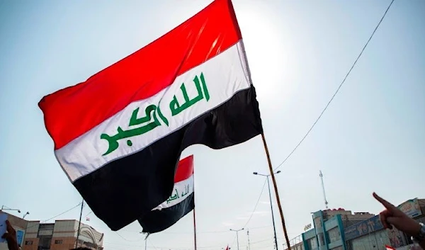 Iraqi flag is raised during protests in Iraq (AFP)