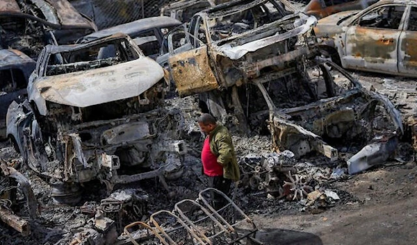 A Palestinian man walks between scorched cars in a scrapyard, in the town of Hawara, near the West Bank city of Nablus, Feb. 27, 2023 (AP)