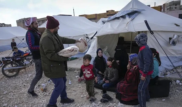 Volunteers distribute bread and other food supplies to those who lost their homes at a camp in Killi, Syria, Sunday, Feb. 12, 2023. (AP)