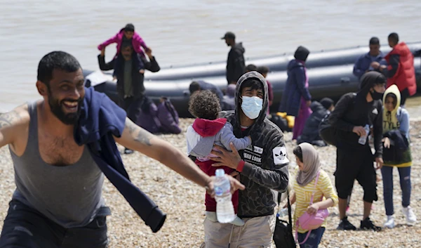 People thought to be migrants make their way up the beach after arriving on a small boat at Dungeness in Kent, England, Monday, July 19, 2021. They were later taken away by Border Force staff. (AP)