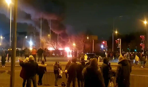 People observe a fire outside a hotel housing asylum seekers after a protest in Knowsley, Merseyside, on 10 February. (Reuters)