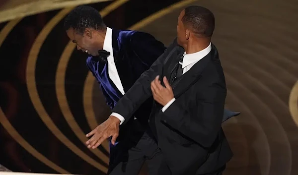 Will Smith, right, hits presenter Chris Rock on stage while presenting the award for best documentary feature at the Oscars on Sunday, March 27, 2022, at the Dolby Theatre in Los Angeles. (AP)