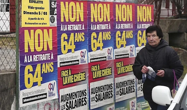 A woman walks past "No retirement at 64" posters in Saint Pee sur Nivelle, southwestern France, Monday, March 6, 2023. (AP)