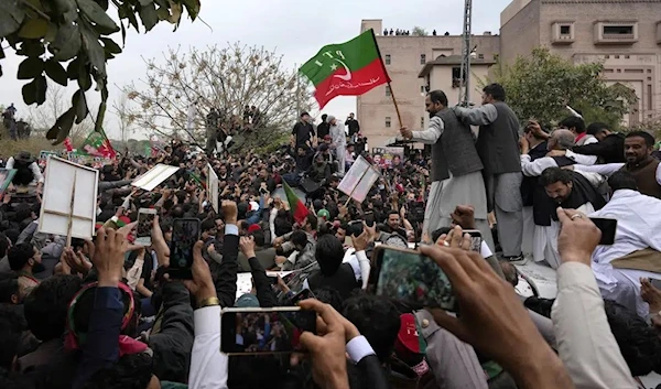 Supporters of former Pakistani Prime Minister Imran Khan move with a vehicle, center, carrying their leader Khan following his court appearance, in Islamabad, Pakistan, Tuesday, Feb. 28, 2023. (AP)