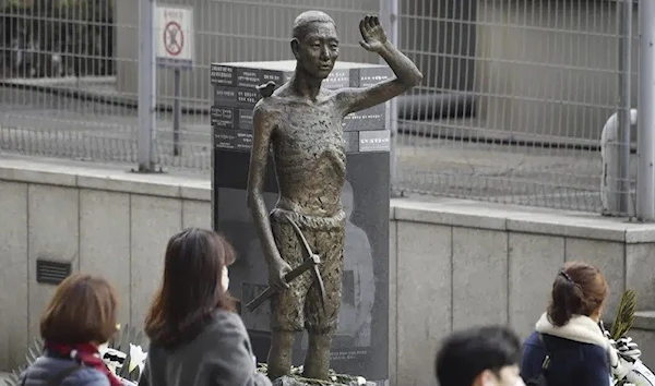 People passing by a statue in Seoul symbolizing forced Korean workers, in March 2023. (AP)