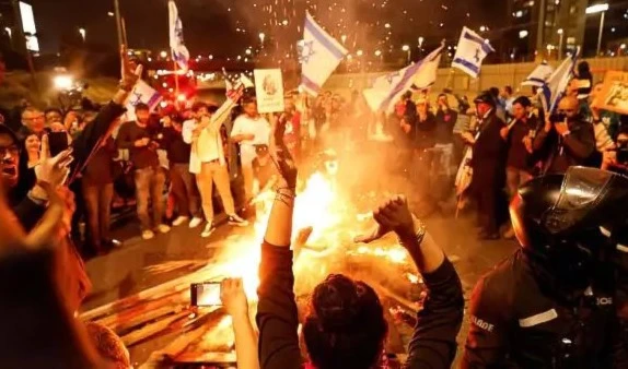 Israeli settlers clash with IOF next to a bonfire in “Tel Aviv” on February 26, 2023. (Reuters)