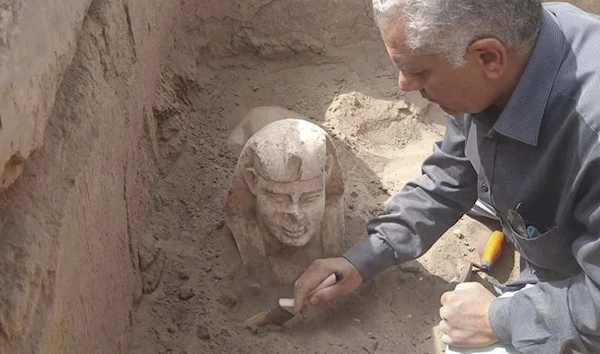 An archaeologist uncovering the ancient sphinx in the excavation area in Luxor, Egypt, March 8, 2023 (AP)