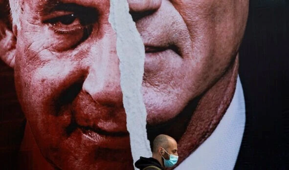 An election campaign billboard for the Blue and White party depicting Benny Gantz and Benjamin Netanyahu hangs on a street in Tel Aviv, March 11, 2021. (AP)