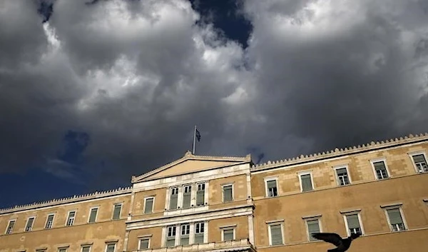 A Greek national flag flutters atop the parliament building in Athens, Greece. (Reuters)