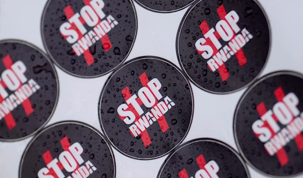 Stickers are covered in rain drops as people protest outside the High Court in London, Monday, Dec. 19, 2022. (AP)