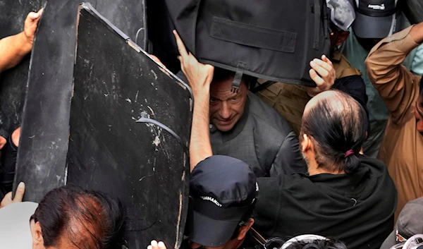 Security personnel hold bulletproof shields to secure former Prime Minister Imran Khan, center, after appearing in a court, in Lahore, Pakistan, Tuesday, March 21, 2023. (AP)