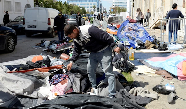 Municipality workers start cleaning a makeshift camp outside the International Organization for Migration office after police forces attempt to evacuate the camp in Tunis, Tuesday, April 11, 2023. (AP)