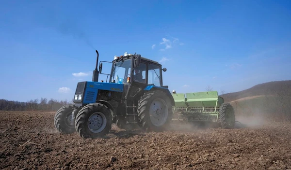 Workers plow wheat on the land belonging to Vasyl Pidhaniak, in Husakiv village, western Ukraine, Saturday, March 26, 2022 (AP Photo/Nariman El-Mofty)