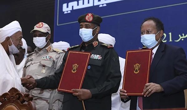 General Abdel Fattah al-Burhan pictured alongside Prime Minister Abdallah Hamdok and Mohamed Hamdan Daglo in a ceremony to reisntate Hamdok who was forced out of office by a coup led by the pair a month before, 25 October 2021. (AP)