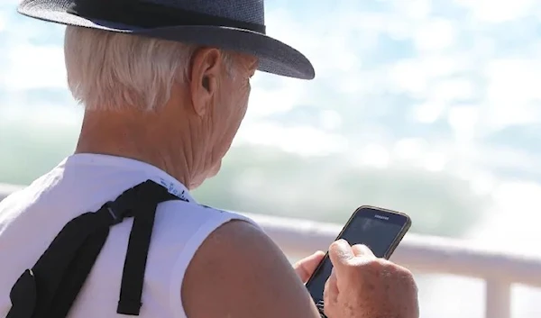 A man with grey hair using his phone (AFP)