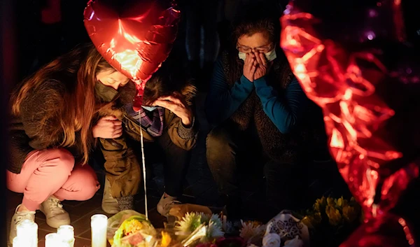 Women pause at a memorial at a vigil honoring the victims of a shooting at the Star Ballroom Dance Studio on January 23, 2023, in Monterey Park, California (AP)