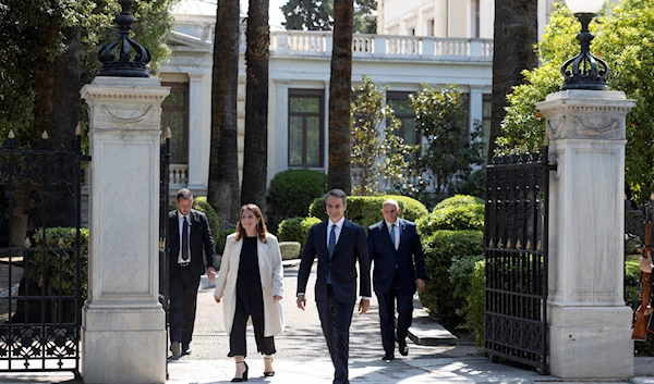 Greece's Prime Minister Kyriakos Mitsotakis, foreground, leaves the Presidential palace following a meeting with Greek President Katerina Sakellaropoulou, in Athens, April 22, 2023 (AP)